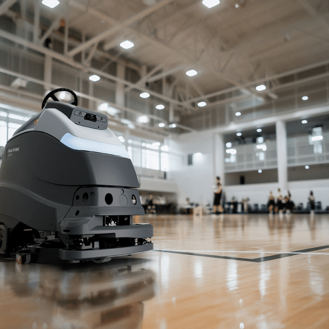 Nilfisk SC50 autonomous floor scrubber cleaning an indoor basketball court