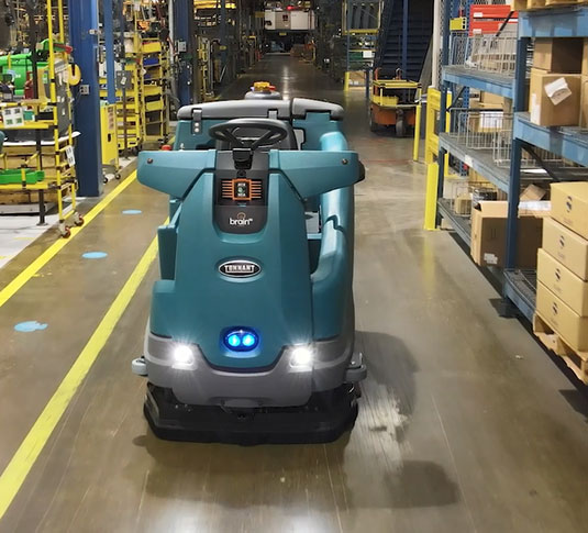 Tennant T16AMR robotic floor scrubber cleaning an aisle at a CNH Industrial distribution facility