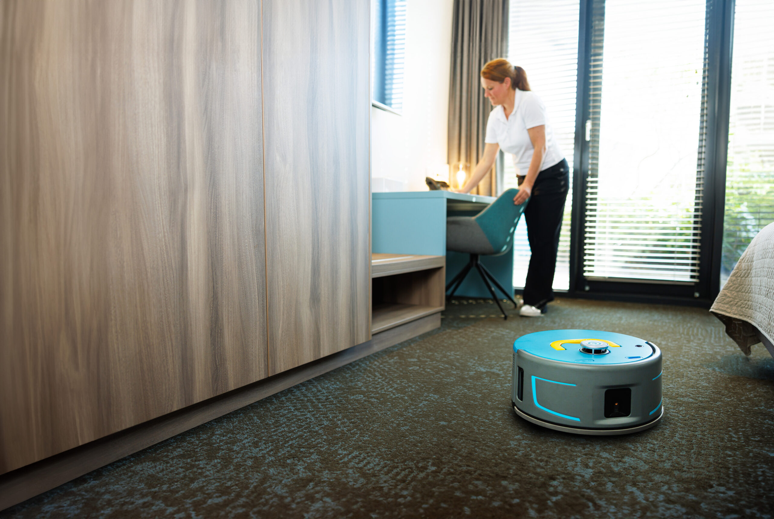 Co-botic 1900 robotic vacuum cleaning carpet in a healthcare patient room.