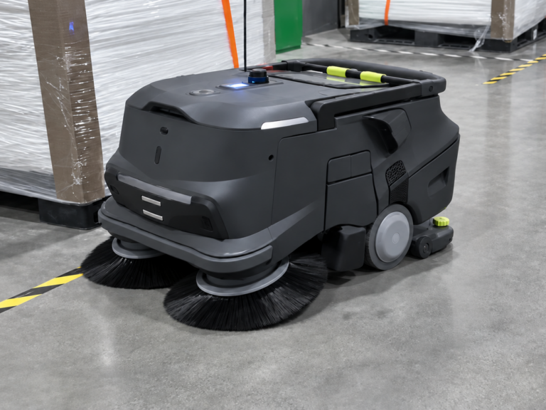 PUDU MT1 industrial robotic sweeper autonomously cleaning a warehouse floor, featuring dual sweeping brushes for efficient commercial floor maintenance.