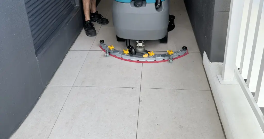Rear squeegee and scrub deck of a Tennant walk-behind floor scrubber on tiled floor in Brisbane