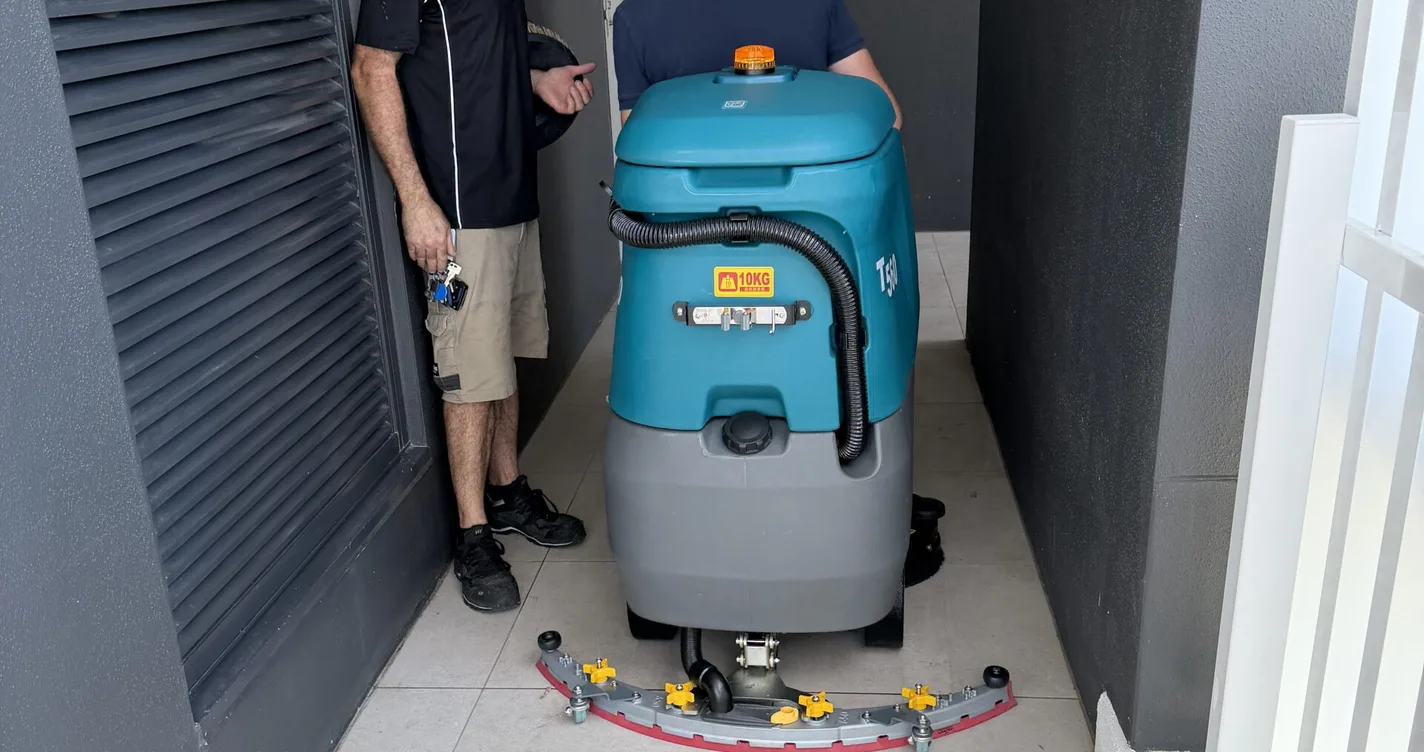 CC Machines technicians with a Tennant T300 walk-behind floor scrubber in a Brisbane building corridor